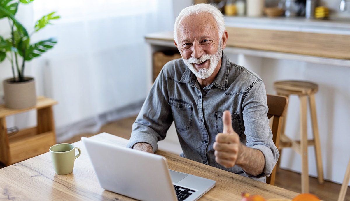 Zufriedener-aelterer-Herr-am-Laptop-ohne-Brille Zufriedener aelterer Herr am Laptop ohne Brille