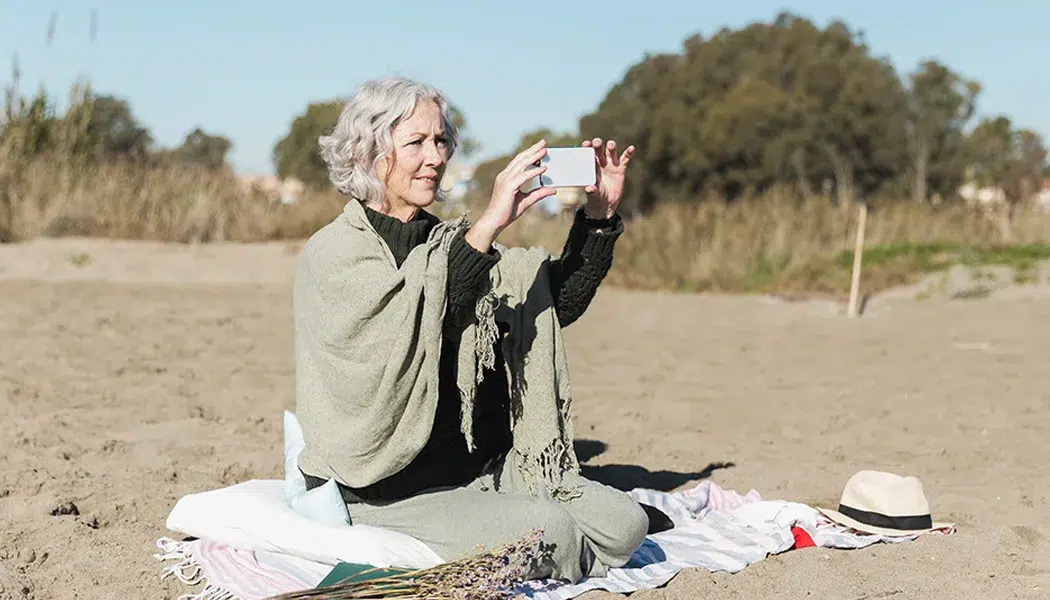 elderly-woman-taking-photos-on-beach elderly woman taking photos on beach